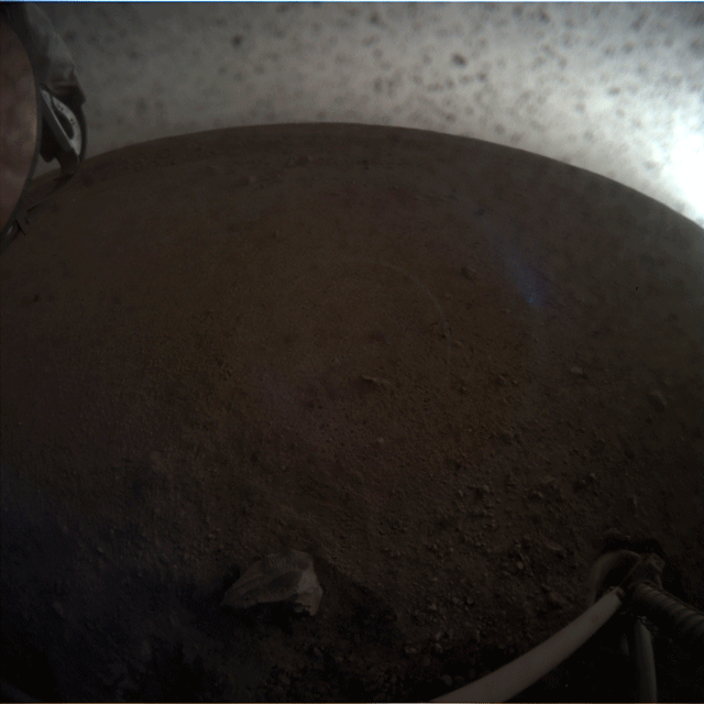 InSight lander deploying its first instrument onto the surface of Mars, taken by the spacecraft's Instrument Context Camera